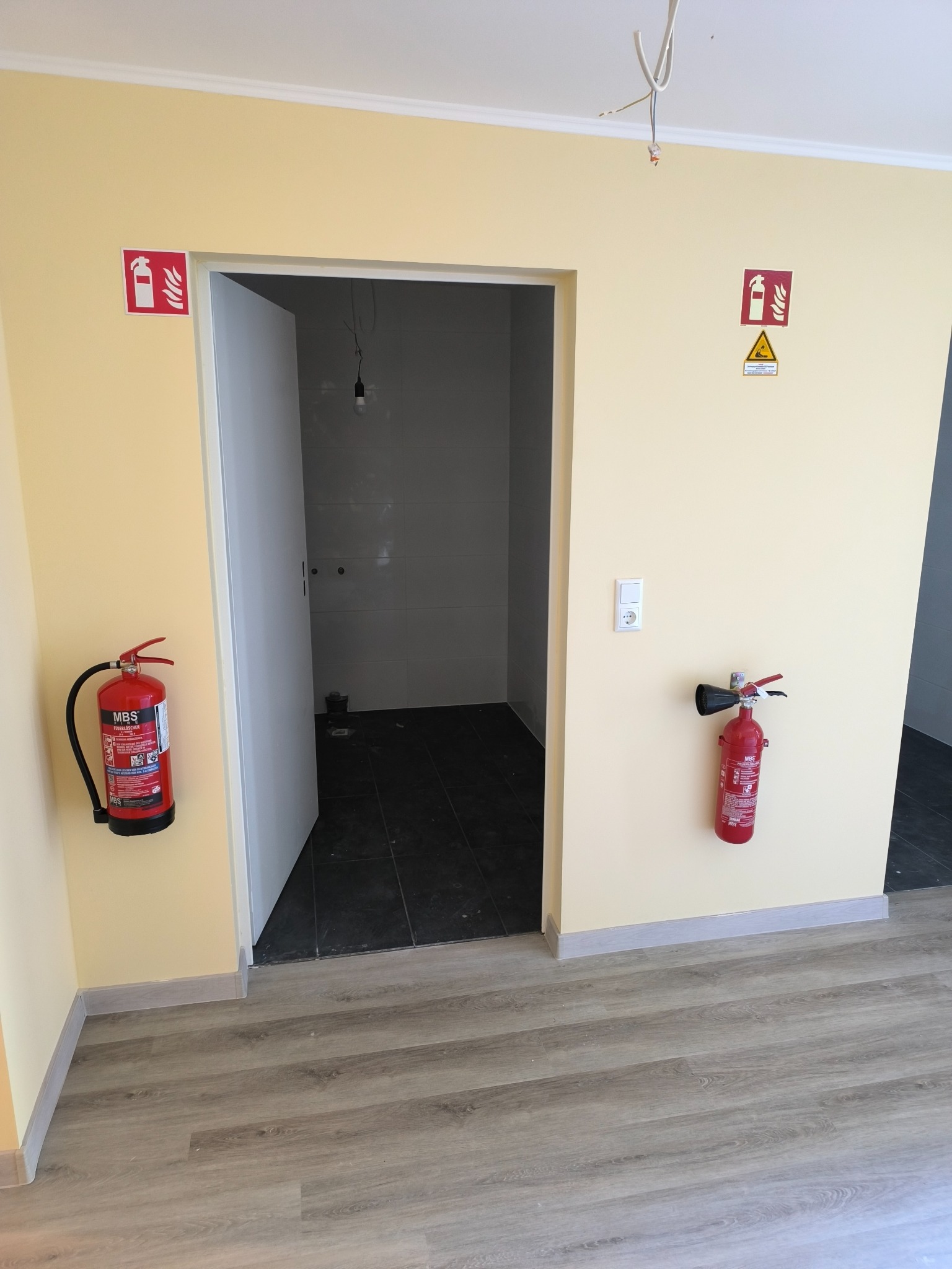 Zwei Feuerlöscher an unterschiedlichen Stellen in einem Flur
